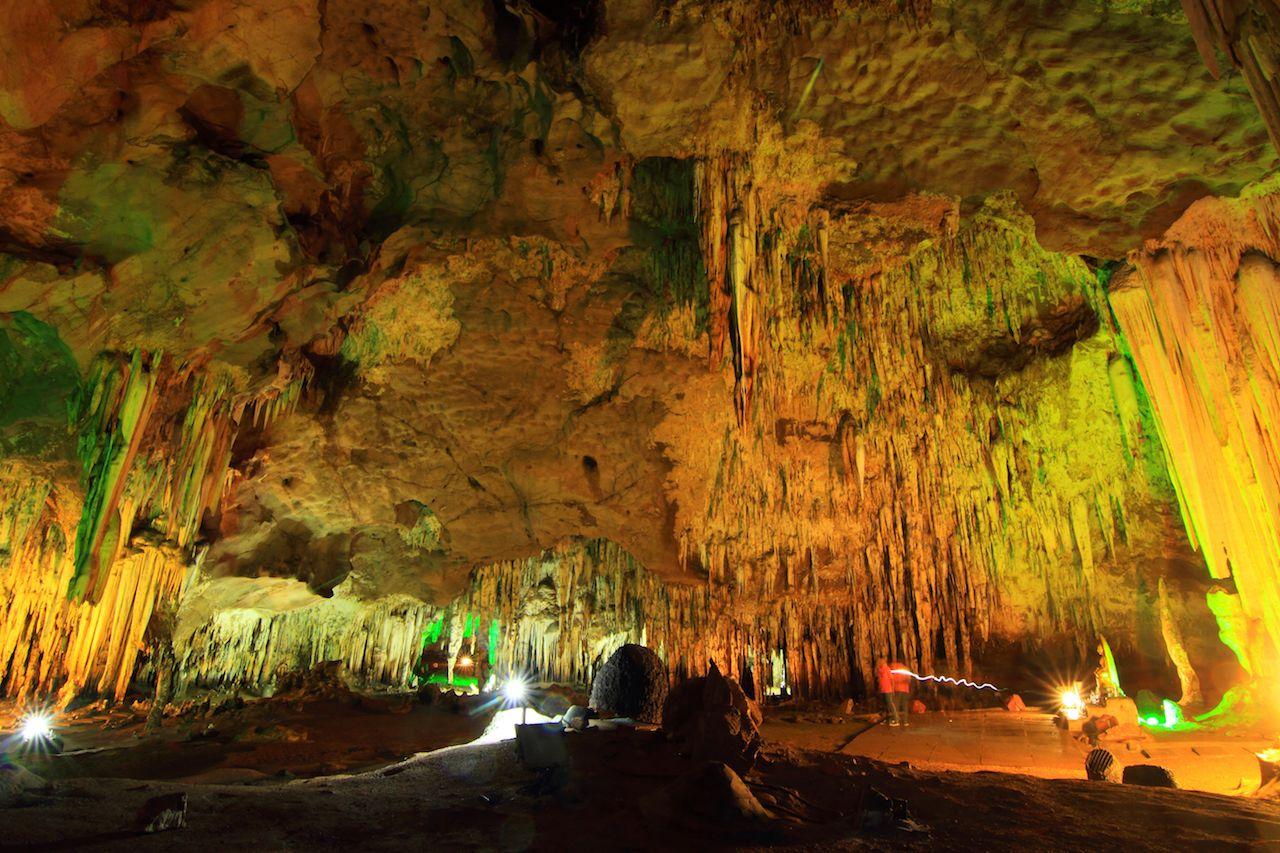 Stalagmit und Stalaktit beleuchtet mit bunten Lichtern in einer Höhle