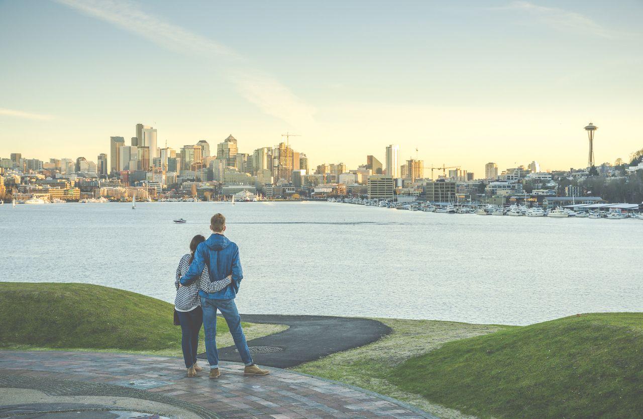 Una coppia si abbraccia e guarda il panorama della città di Seattle al tramonto. Le migliori destinazioni per babymoon