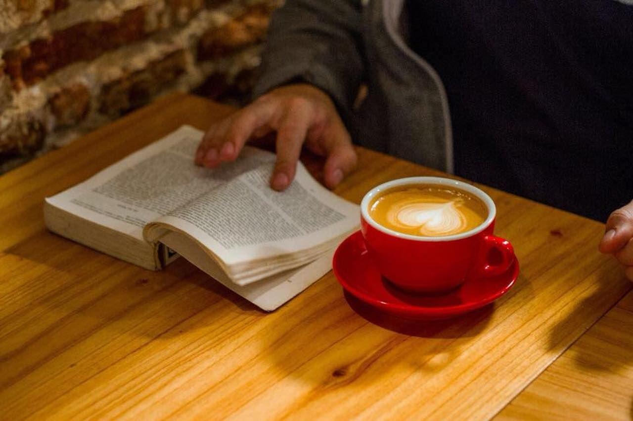 Persona che legge un libro con caffè